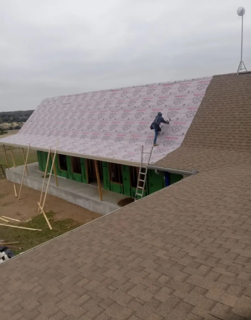 Worker preparing underlayment for a metal roof installation in Apex
